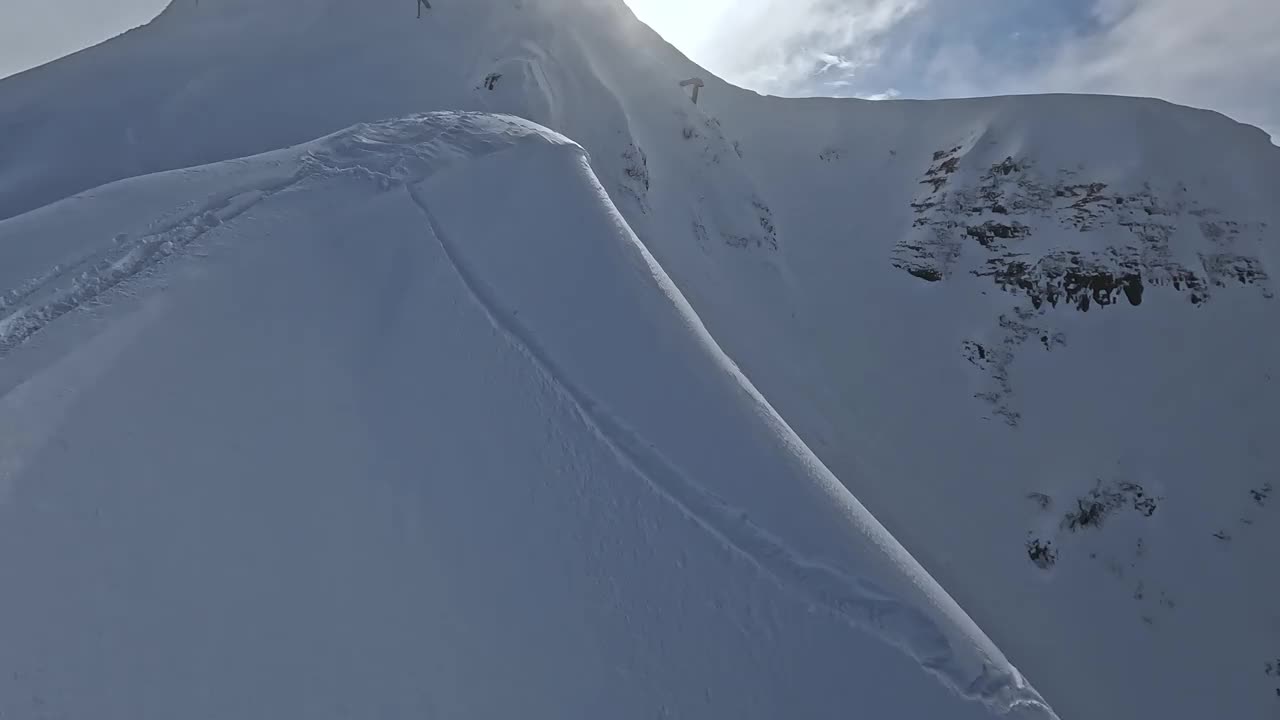 极限滑雪板男穿着运动服头盔站在雪山山顶坡脊鸟瞰视频素材