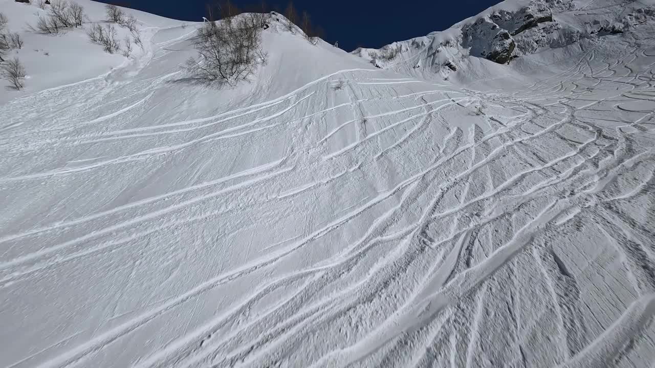 雪山斜坡接近山顶与两个活跃的人在山顶雪道鸟瞰视频素材