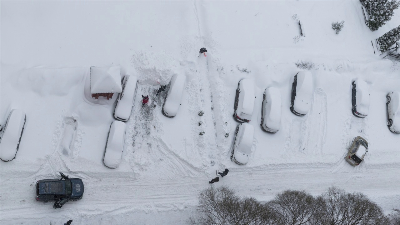 时间流逝。大雪期间，清洁工正用铁锹清理一家多商店大楼院子里被雪覆盖的停车位。视频下载