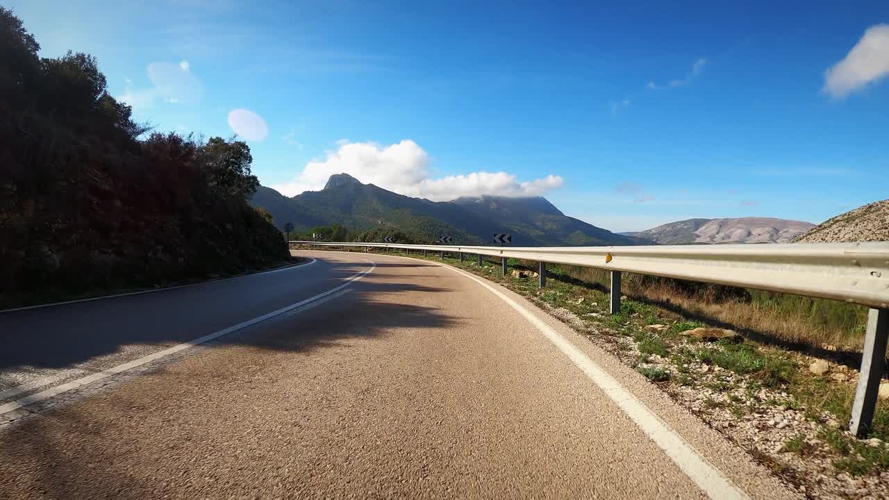 在阳光下，行驶在蜿蜒的森林道路上。美丽弯曲的山路视频素材