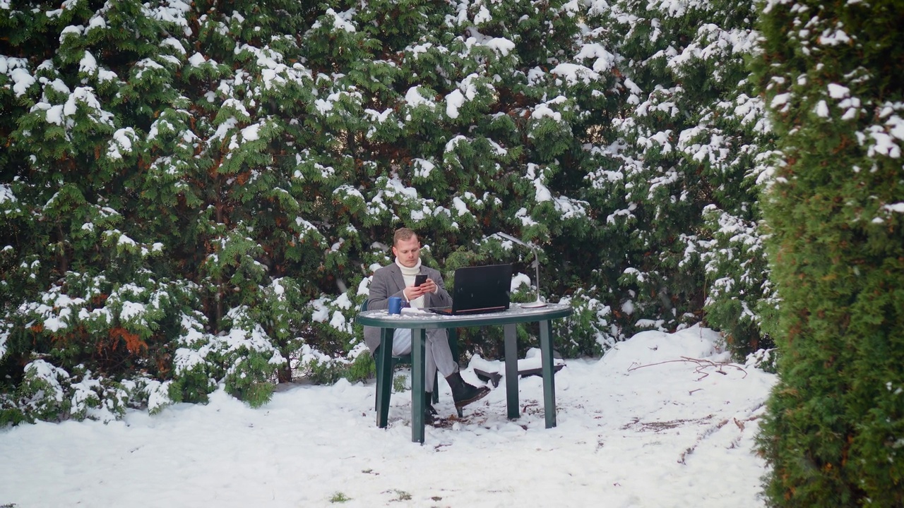 在乌克兰停电时，沮丧沮丧的商人在花园工作，在冬天寒冷的雪下在室外用手机打字视频素材