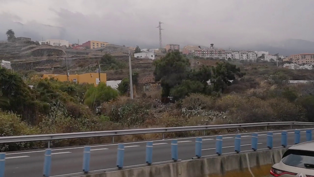 在多云的雨天，从行驶中的巴士侧窗看特内里费岛的异国风景，12秒视频素材