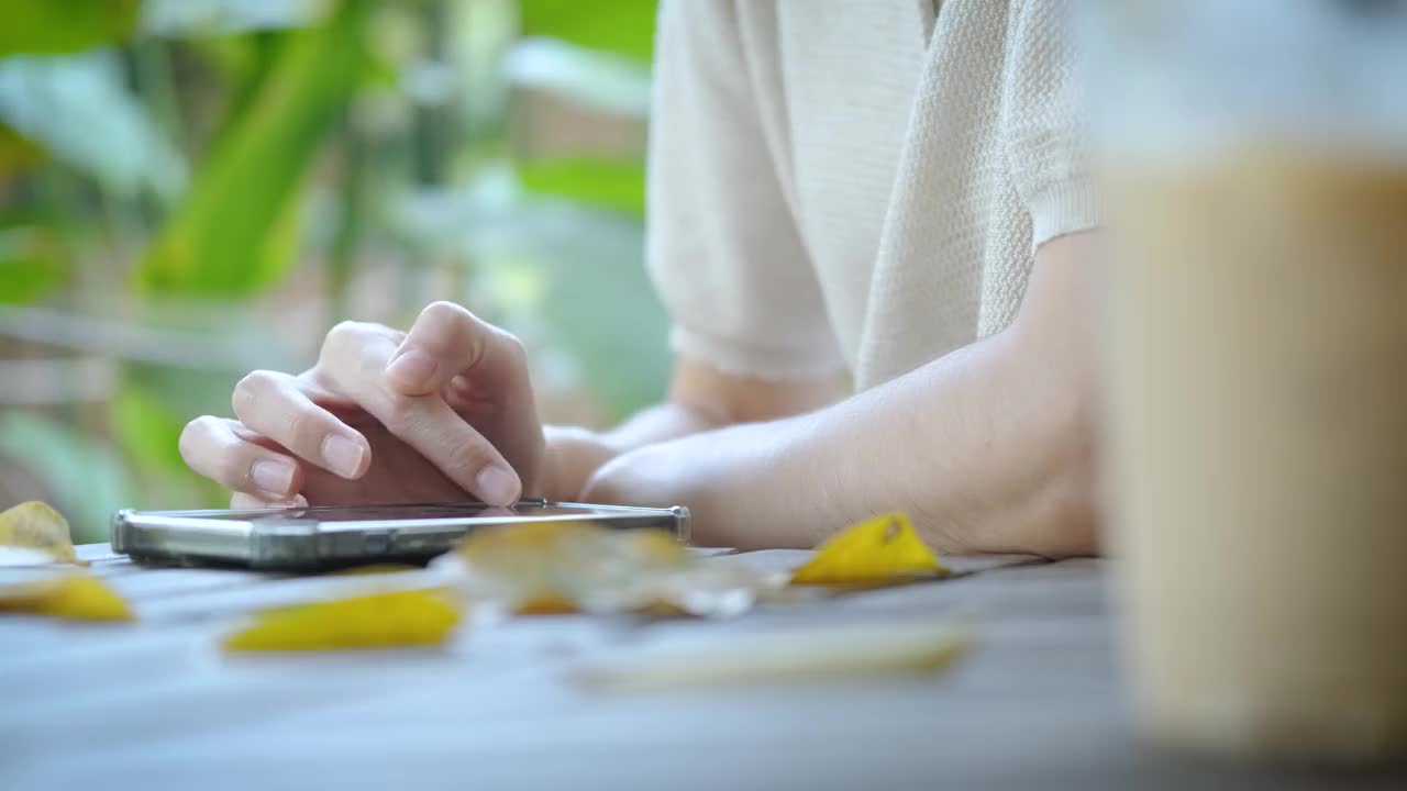 商务女性的手在工作或网上购物从咖啡店在假期期间被花园树木和放松的气氛包围。视频素材