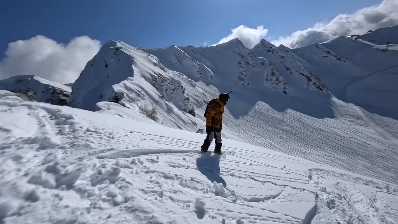 男子单板滑雪自由式骑行从山顶上的雪地极限运动旅游鸟瞰图视频素材