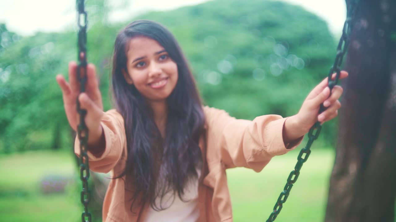 一名年轻女子在公园的秋千上荡秋千视频素材