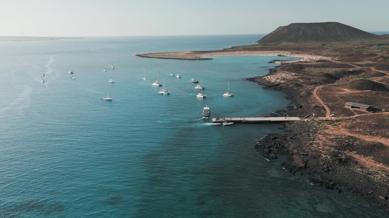 在Corralejo Fuerteventura附近，码头和船只停泊在美丽的Lobos岛附近，令人惊叹的空中轨道视图视频素材