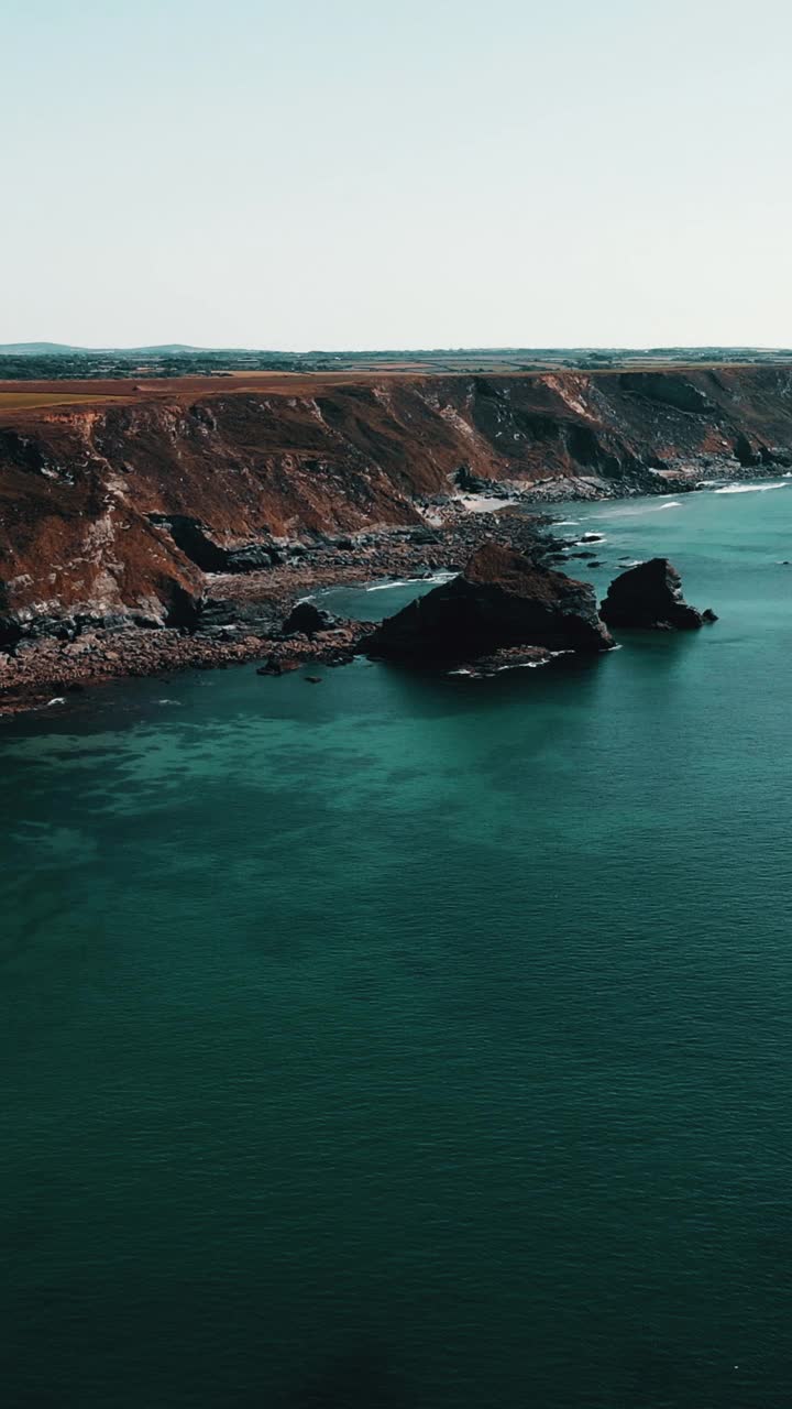 海洋海岸线的岩石与蓝绿色的水垂直视频视频素材