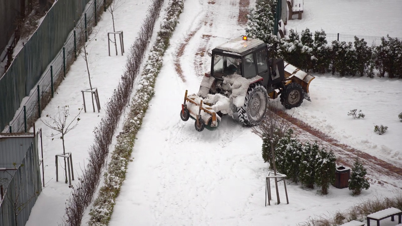 在城市里，拖拉机用刷子清理积雪视频素材