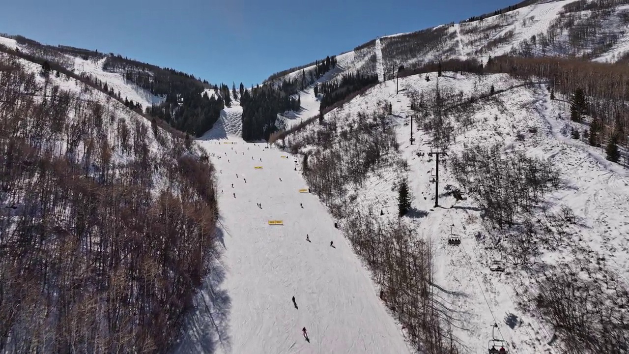 犹他州帕克城空中v2低空立交桥山地滑雪场，在阳光明媚的冬天捕捉下坡滑雪者和上坡索道升降机-用Mavic 3 Cine拍摄- 2022年2月视频素材