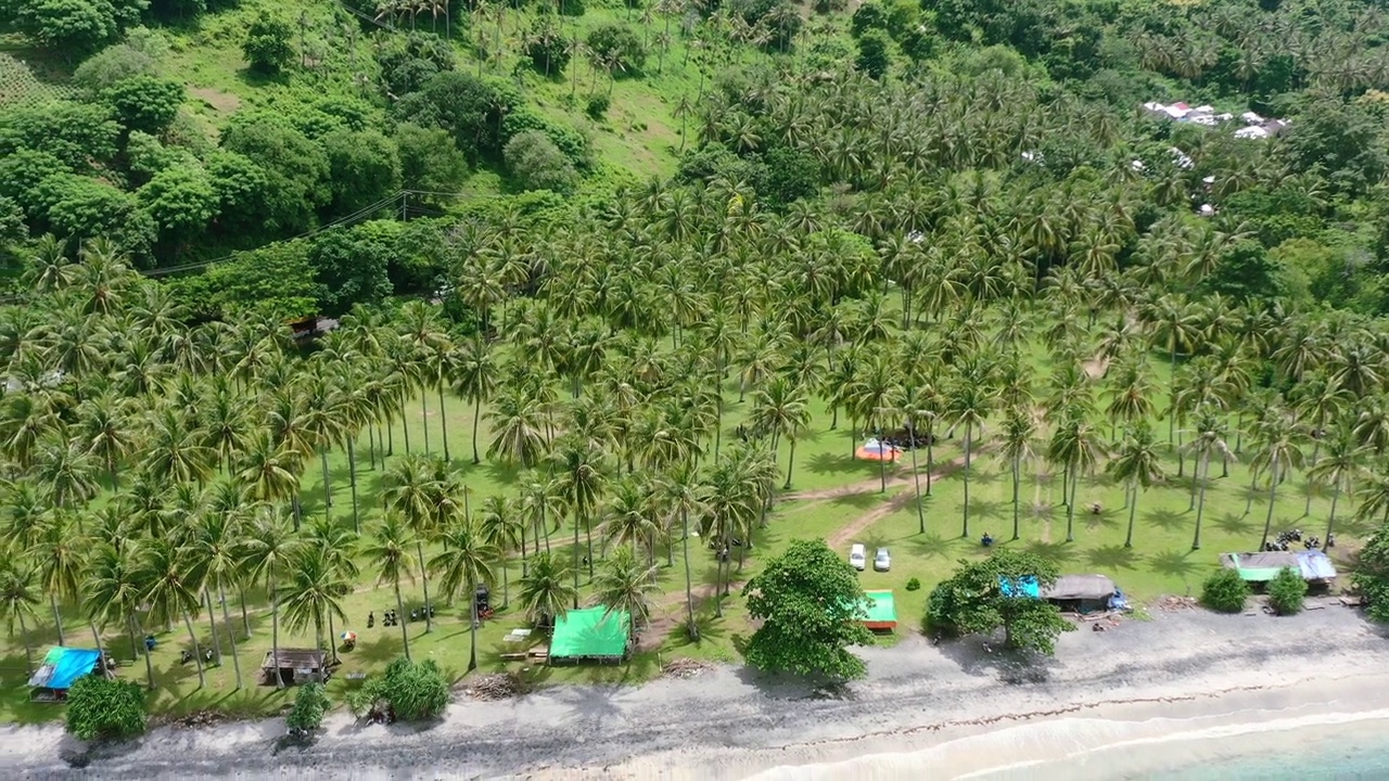 在圣吉吉龙目岛的克兰丹甘海滩上的热带椰子树，空中拍摄视频素材