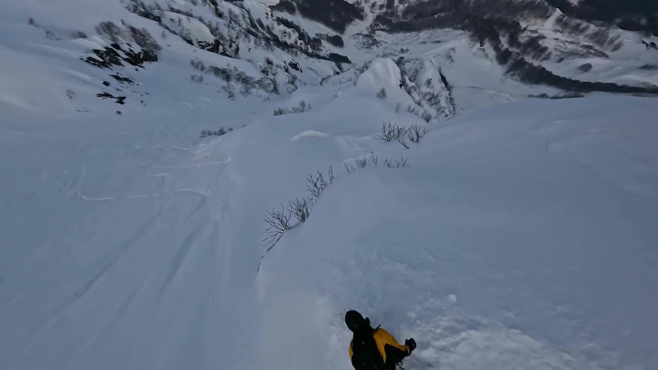 男子骑滑雪板自由式技巧山脉山脊雪上飞溅坡极限运动鸟瞰图视频素材