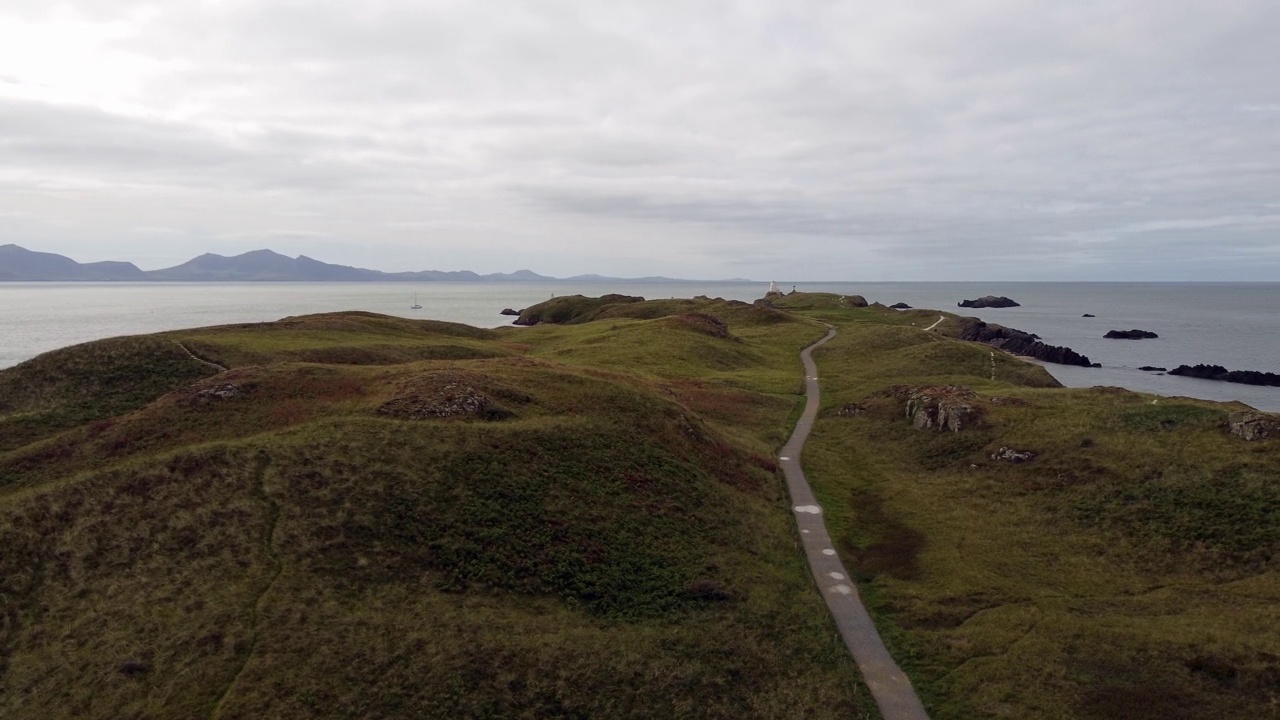 鸟瞰图Ynys Llanddwyn岛安格尔西岛海岸步道与斯诺登尼亚山脉横跨爱尔兰海轨道左侧视频素材