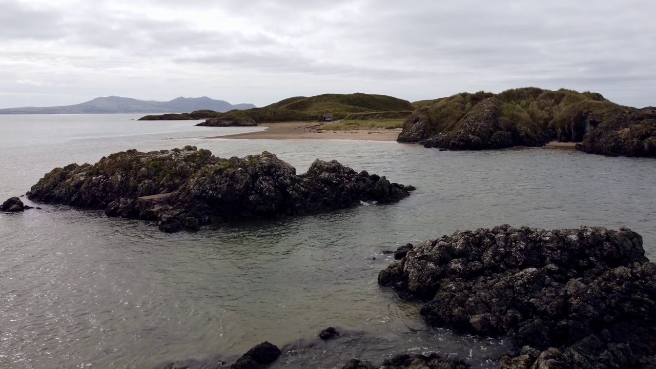 鸟瞰图Ynys Llanddwyn岛安格尔西岛沿海步行小径与斯诺登尼亚山脉低空飞越爱尔兰海视频素材