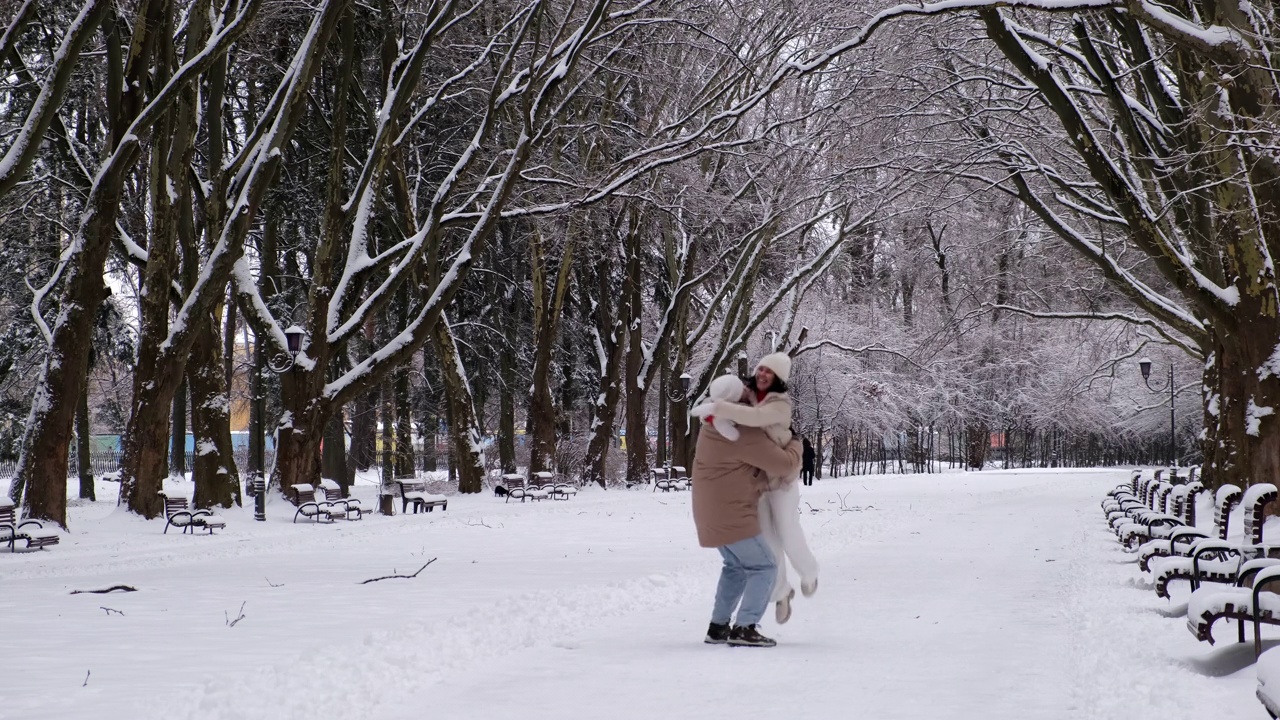 一对情侣在大雪纷飞的冬日在城市公园散步视频素材