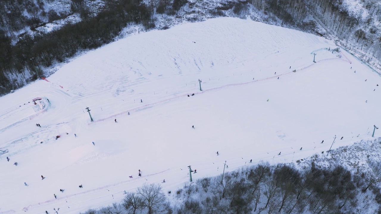 白雪覆盖的滑雪场，滑雪者和滑雪板选手。人们在雪地上滑雪，无人机在空中拍摄。视频素材