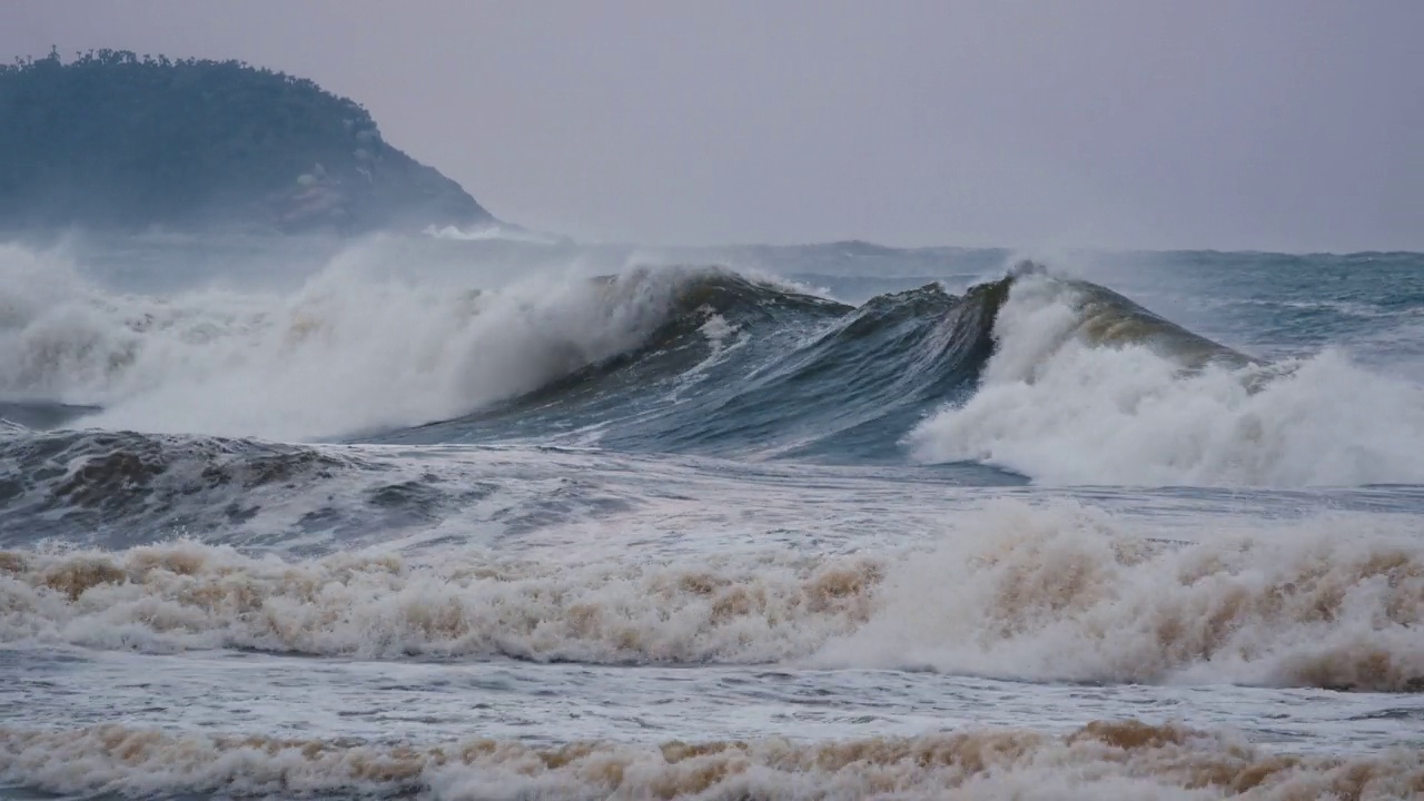 大浪带着泡沫和污垢在大海中移动，在强烈的风暴中打破岩石视频素材