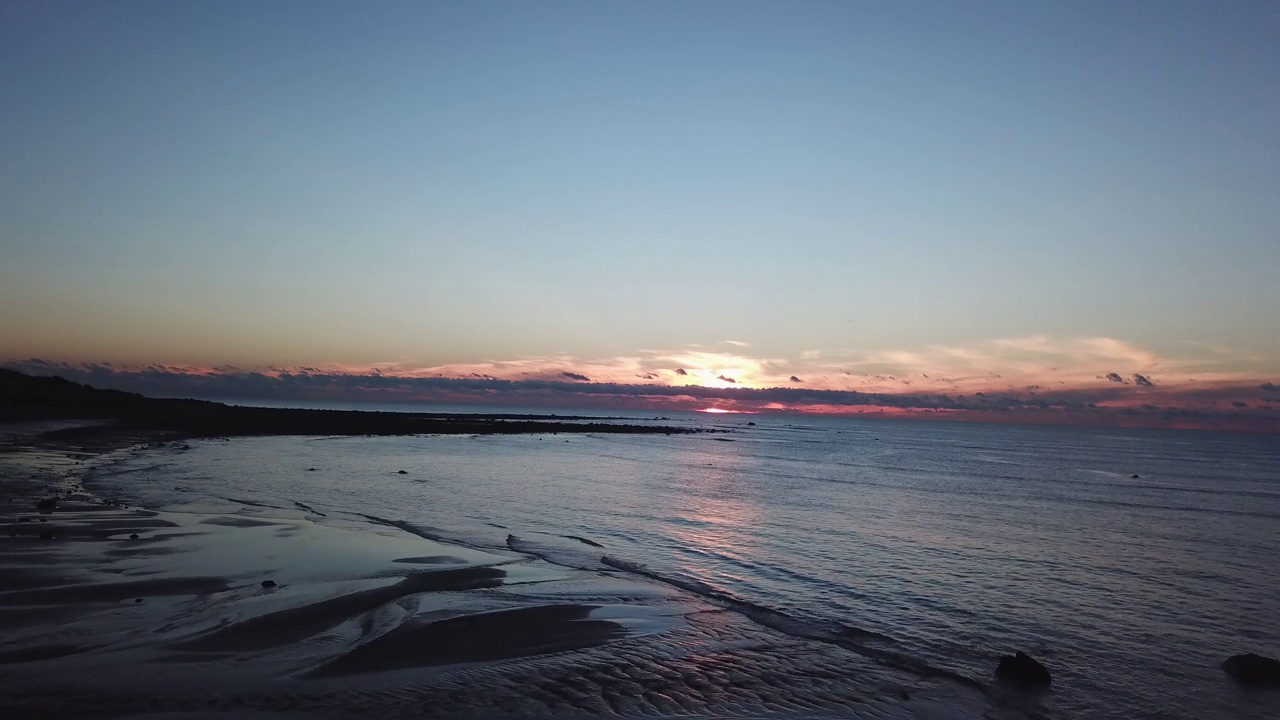 日落时分，海浪平静地在沙滩上翻滚的无人机镜头视频素材