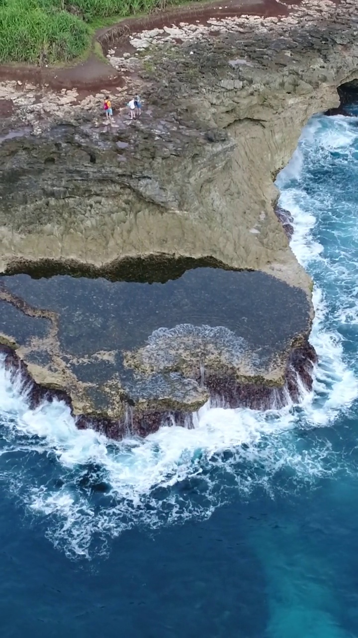 垂直航拍的岩石海岸与海浪碰撞的视频视频素材