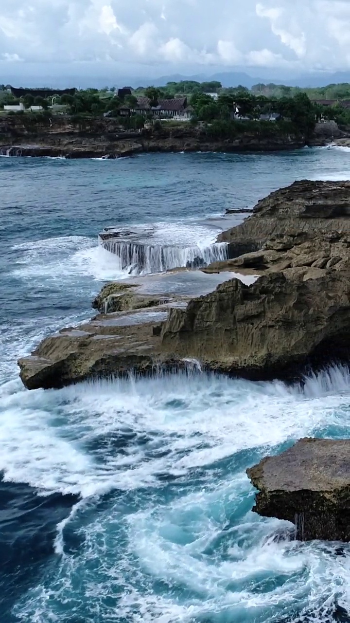 垂直航拍的岩石海岸与海浪碰撞的视频视频素材