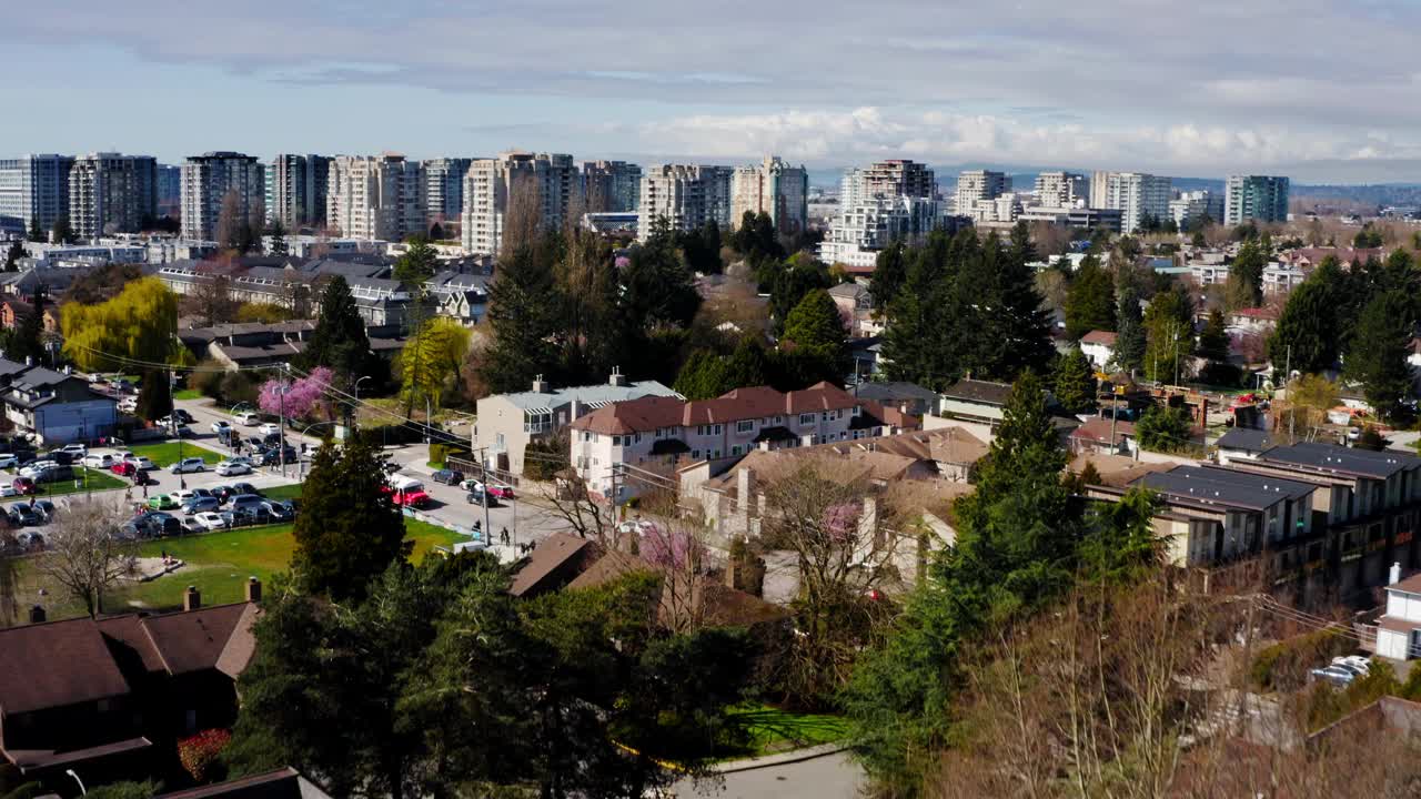 在加拿大卑诗省里士满市高层建筑附近的社区街道上行驶的汽车。——空中视频素材