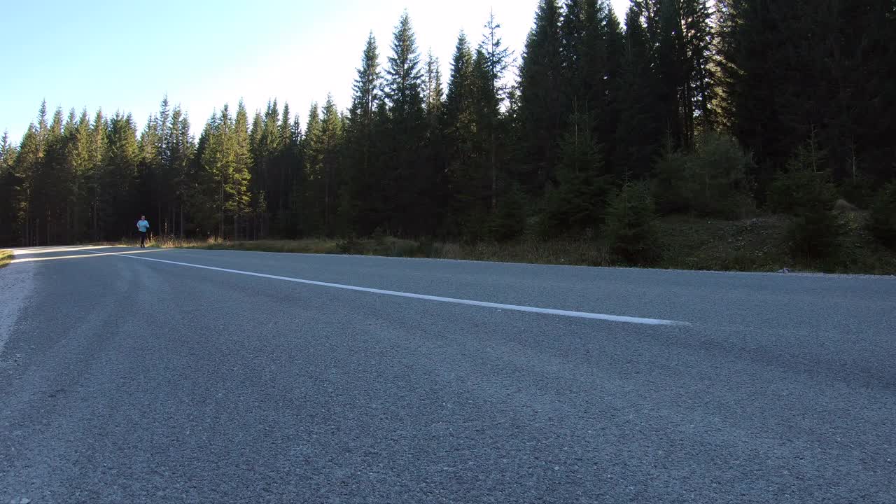 白人运动女性在森林树木之间的道路上跑步在早晨视频素材