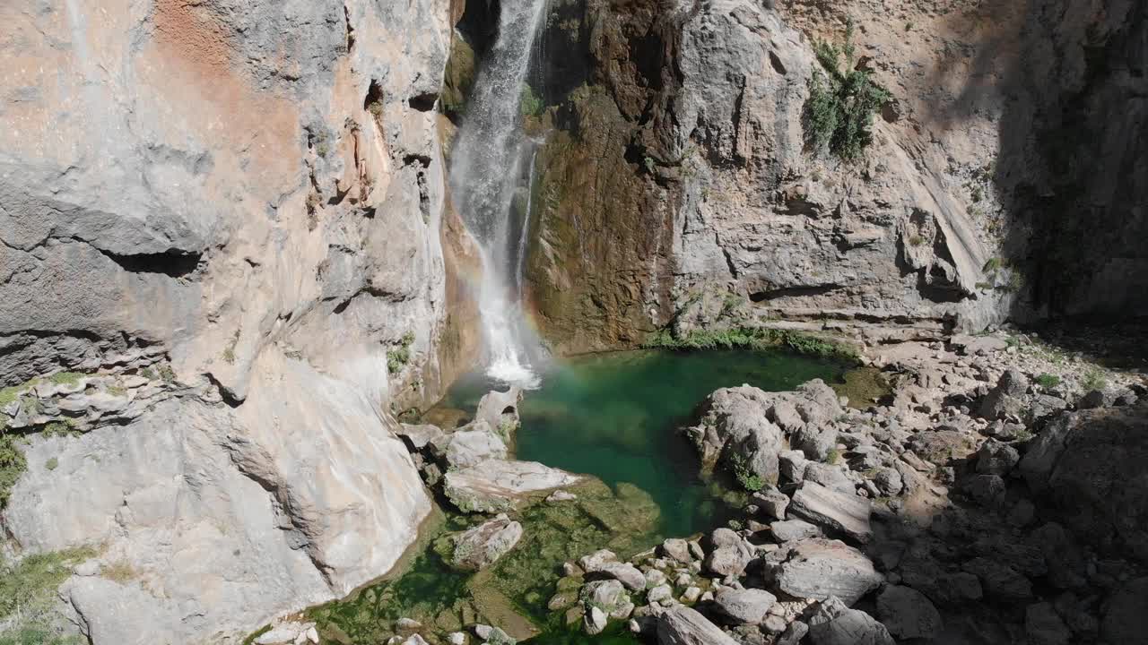 在瀑布底部的悬崖上，淡水从悬崖上滴下来，在岩石上雕刻出一个湖泊，形成一个池塘，一个充满异国情调的绿色池塘。视频素材