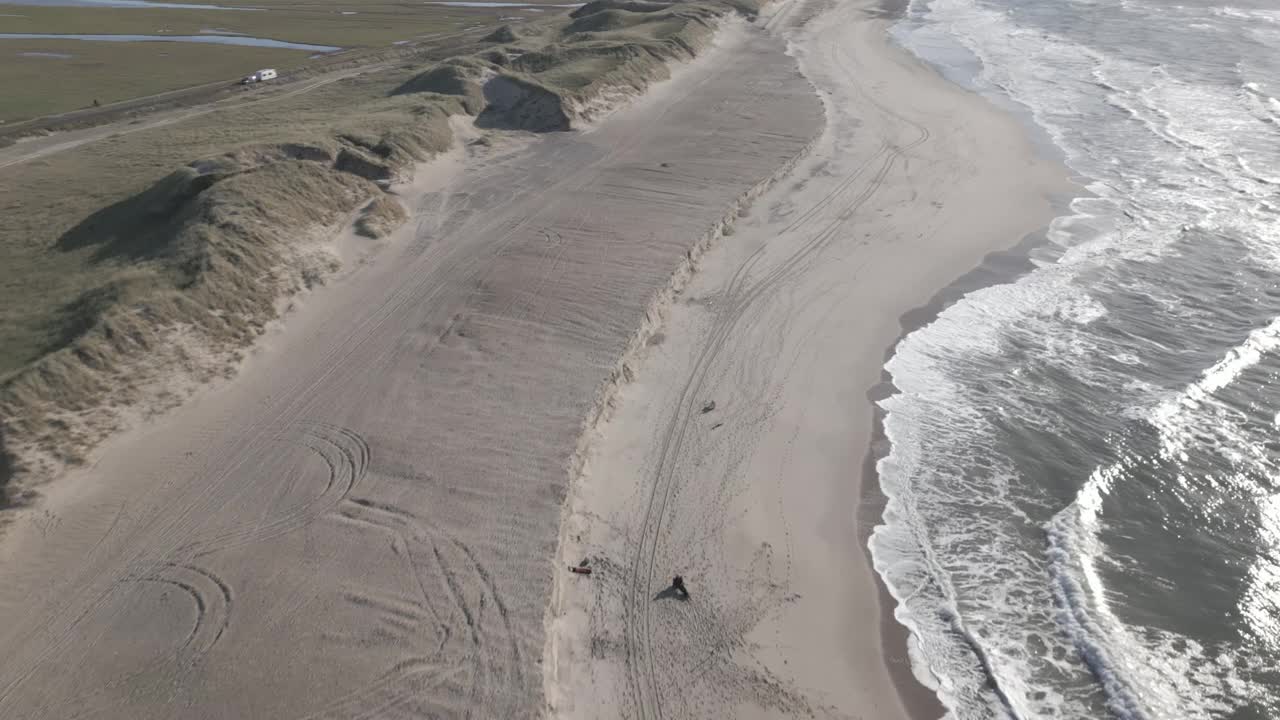 航拍的海浪在沙滩上与绿色沙丘在一个阳光灿烂的日子在丹麦视频素材