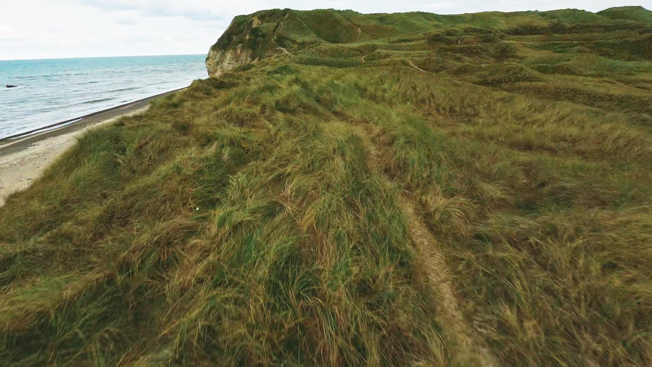 在海边长满草的悬崖上飞驰的无人机视频素材