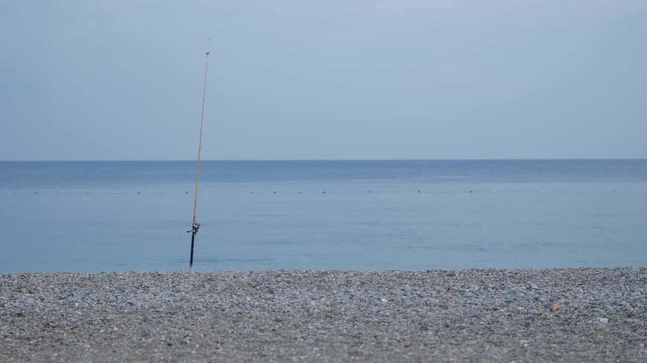 一根鱼竿卡在海边海滩的地上视频素材