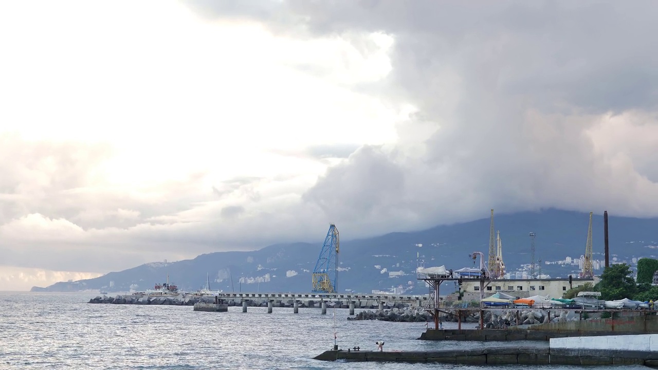 从海边海滩的顶端可以看到悬崖峭壁和码头。美丽清澈的黑海。夏季多云多浪。周末在海边视频素材