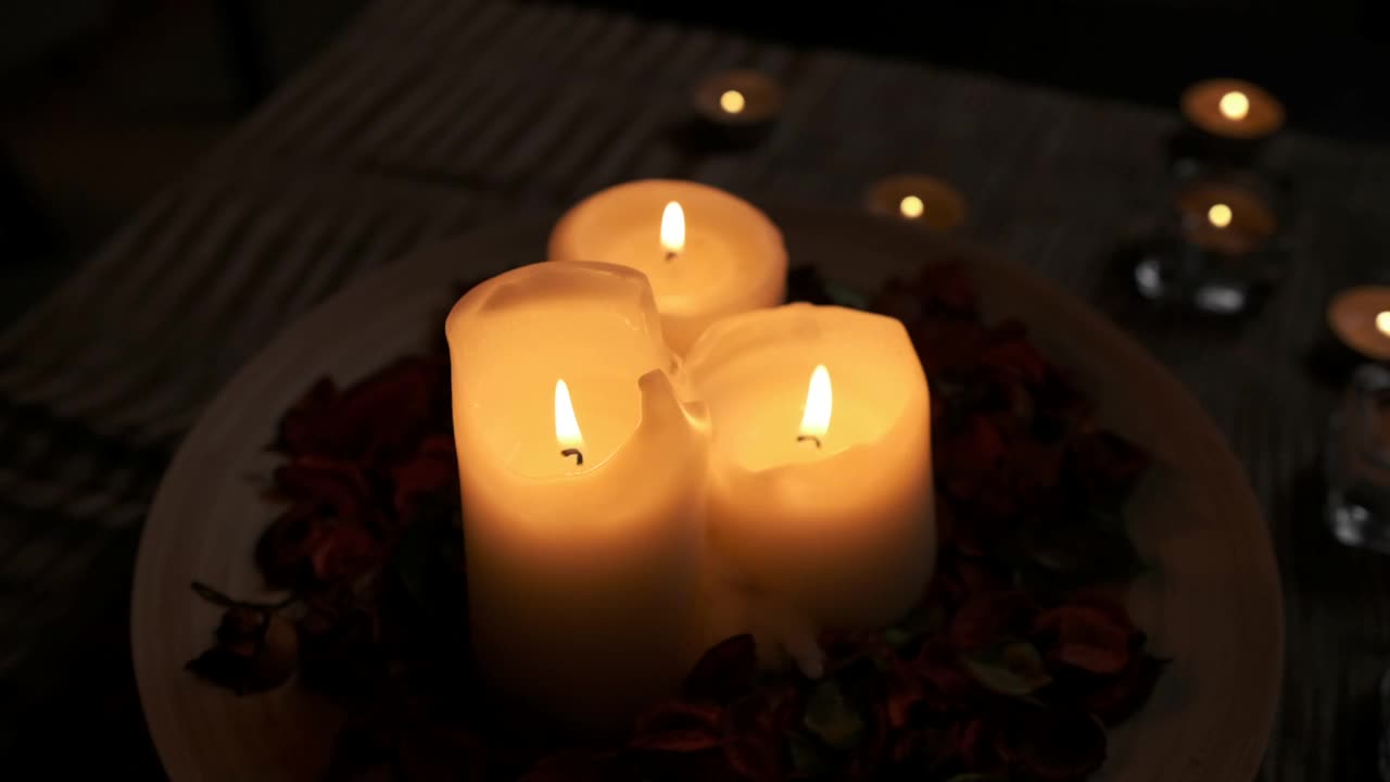在高清法拍摄的木桌上被花瓣包围的点燃的蜡烛特写视频素材