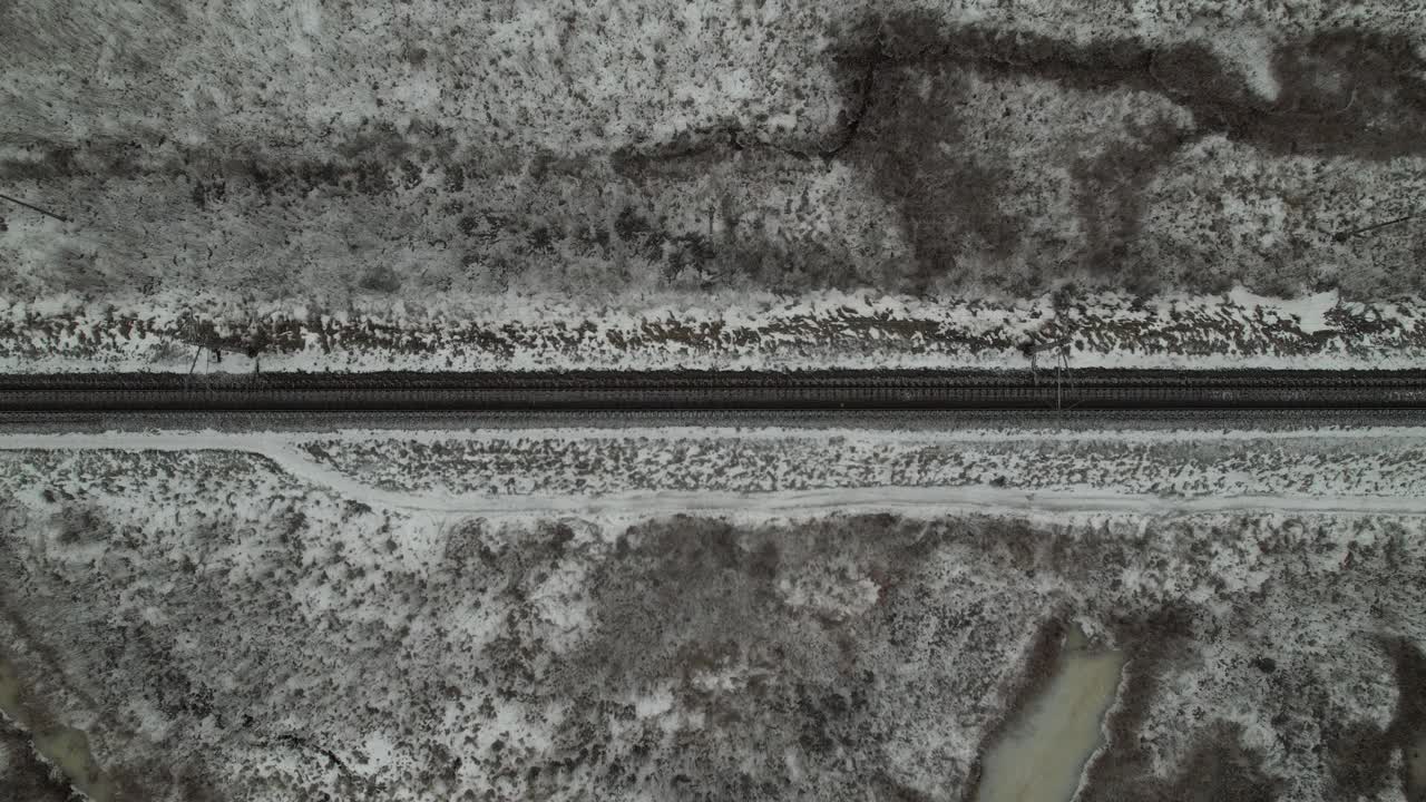 白天，火车通过雪域和道路的俯视图视频素材