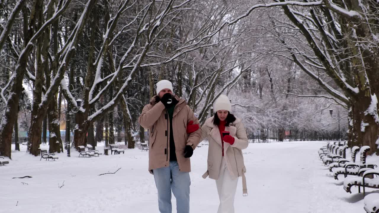 一对情侣在大雪纷飞的冬日在城市公园散步视频素材