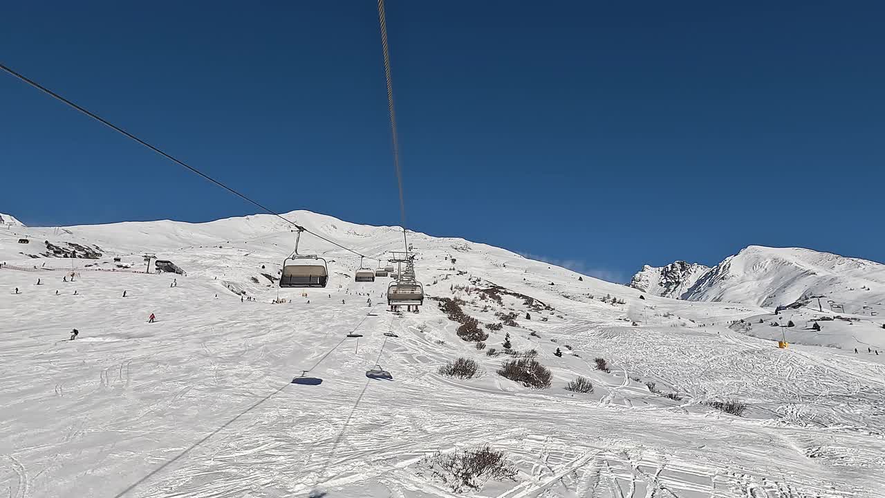 Passo del Tonale, Ponte di Legno，意大利。在一个阳光明媚的日子里，滑雪者在缆车上移动到滑雪道的顶部。最佳滑雪场视频素材