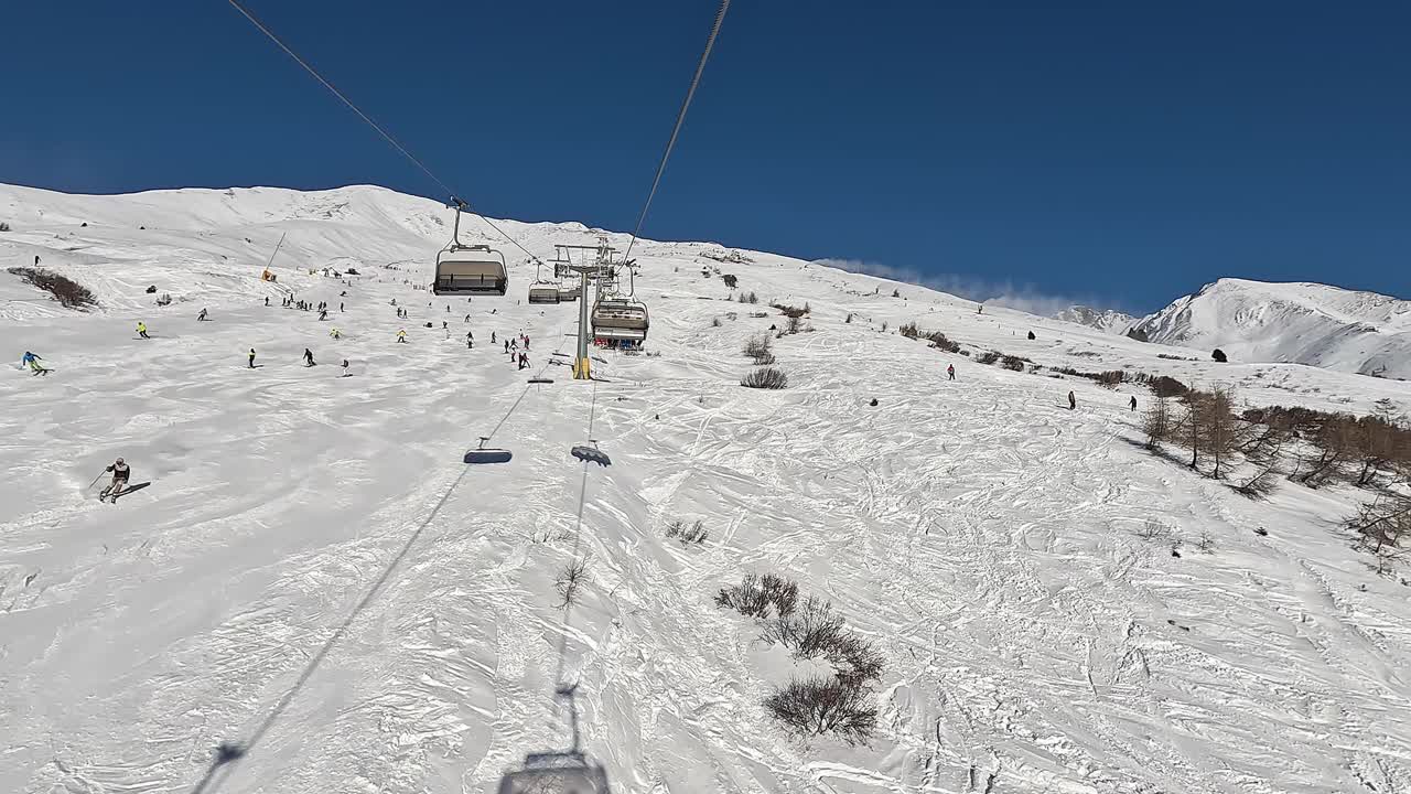 Passo del Tonale, Ponte di Legno，意大利。在一个阳光明媚的日子里，滑雪者在缆车上移动到滑雪道的顶部。最佳滑雪场视频素材