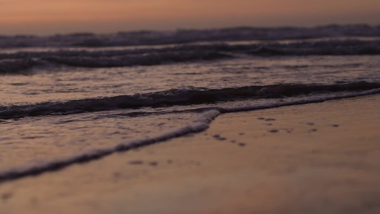 日落时分海浪冲刷沙滩的慢镜头视频素材