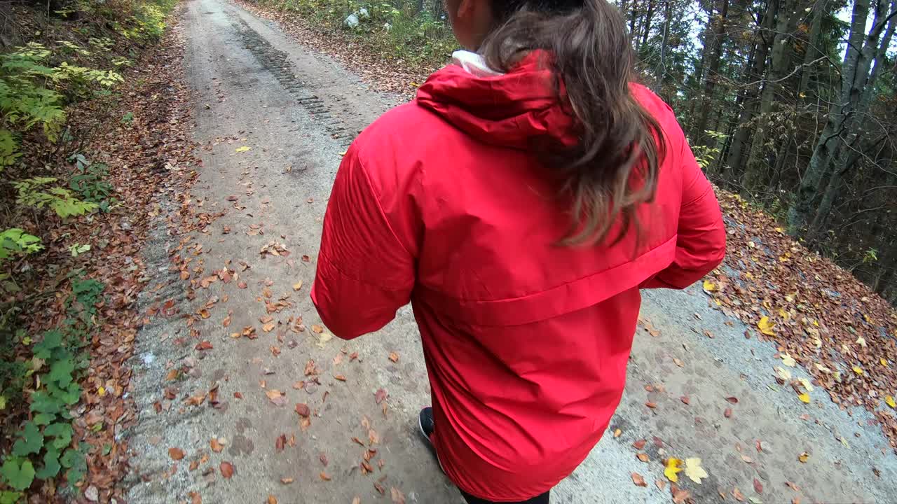 穿着红色运动服的年轻女子在树林间的狭窄道路上奔跑视频素材