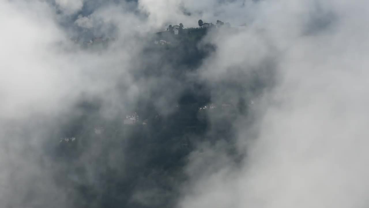 鸟瞰山顶上被雾气笼罩的乡村房屋，周围都是植被视频素材