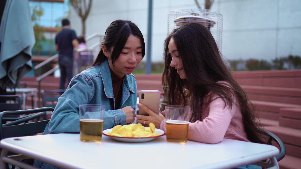 两名年轻女子正在用智能手机看照片视频素材