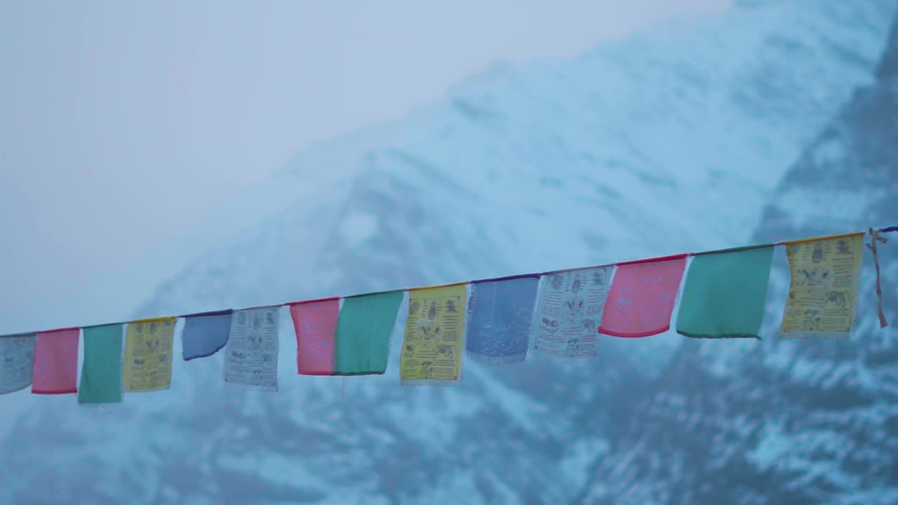 在印度喜马偕尔邦的拉胡尔斯皮提，佛教经幡在积雪覆盖的喜马拉雅山峰前的特写镜头。在冬天，山前的经幡。视频素材