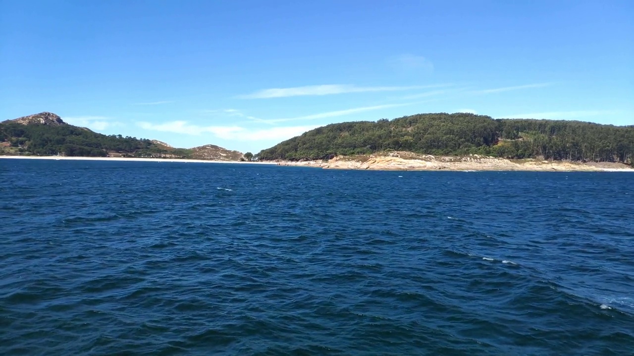 hill in the Cíes Islands, the beach and forest of the biosphere reserve, natural fauna in the background, sunny day of blue sky, blocked shot traveling diagonally forward, Pontevedra, Galicia, Spain视频素材