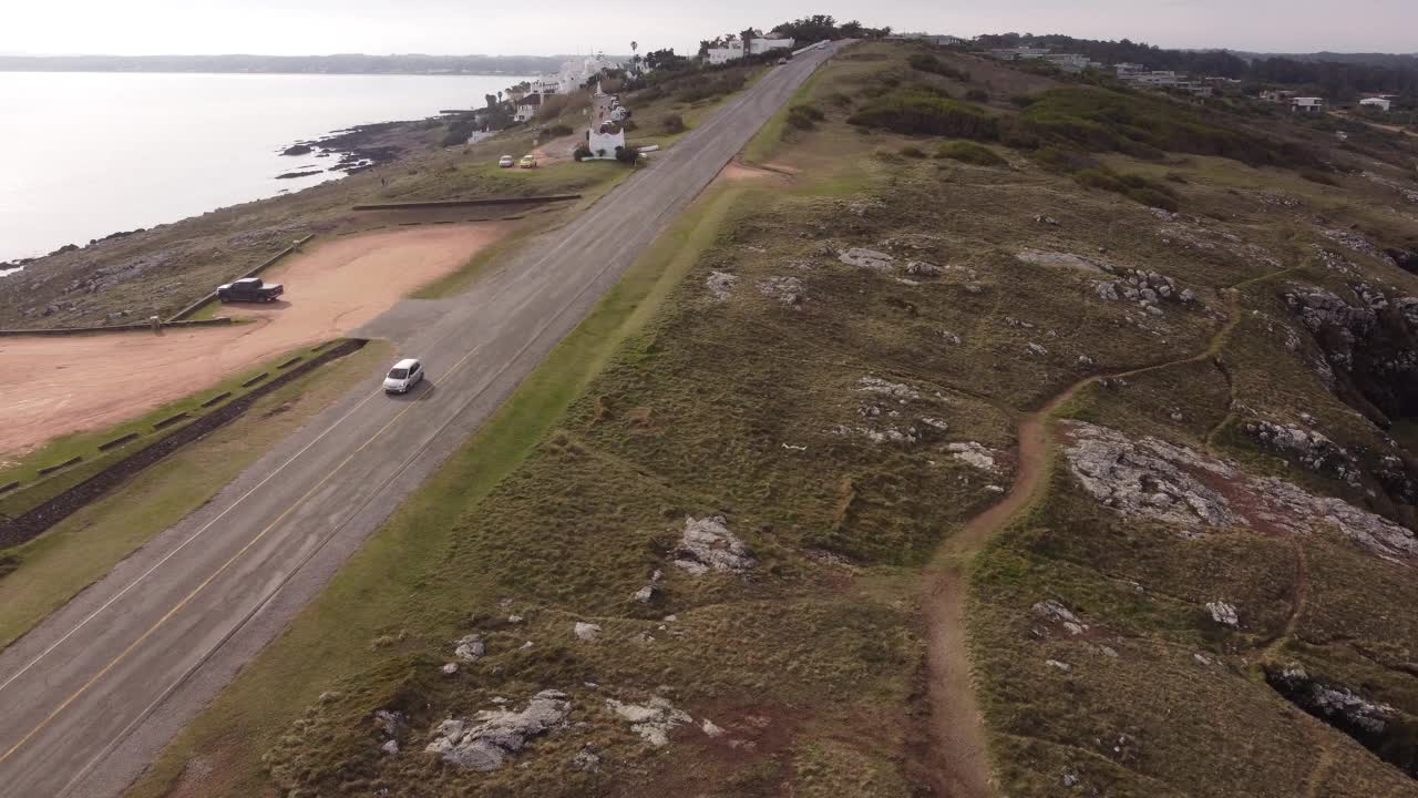 沿着乌拉圭埃斯特角城蓬塔巴莱纳半岛沿海公路行驶的汽车。空中自顶向下轨道视频素材