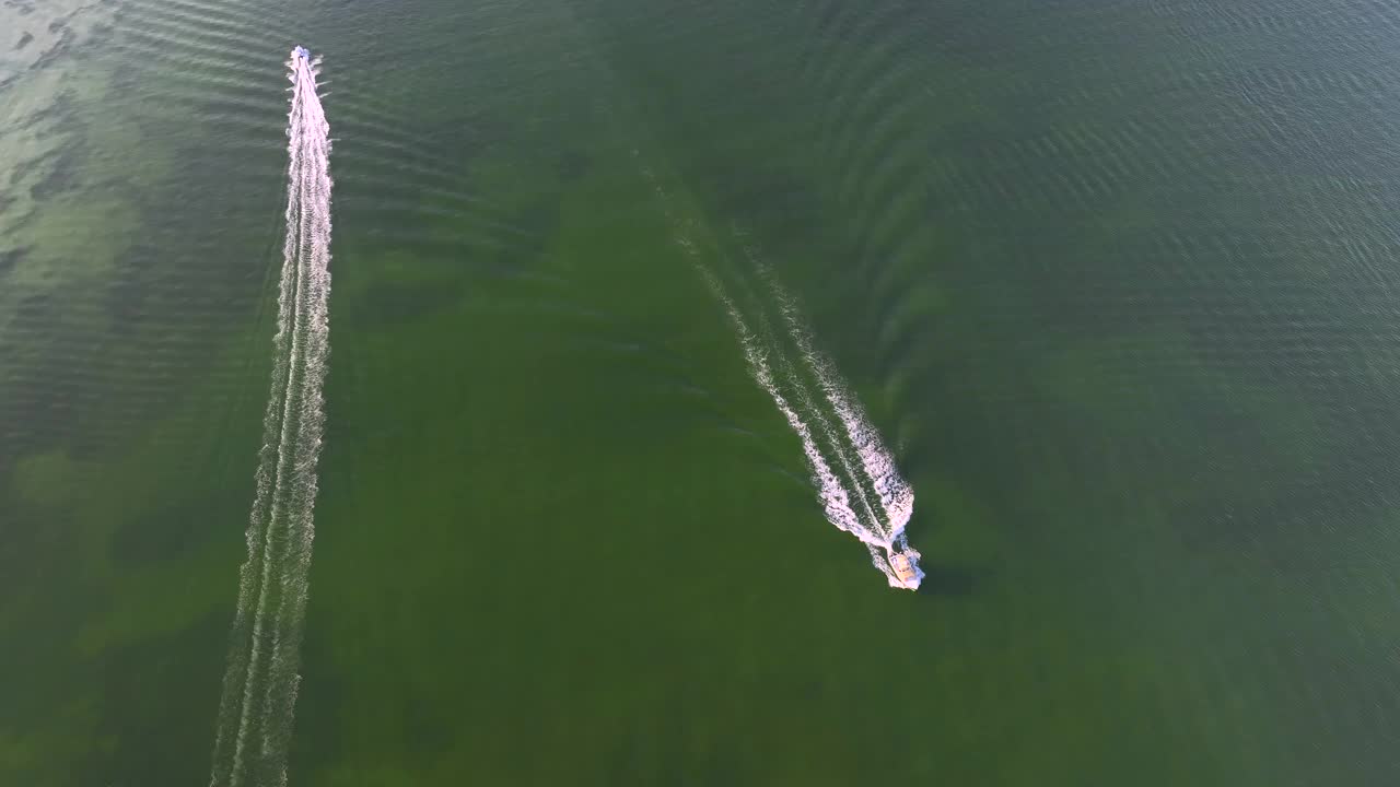 鸟瞰白色快艇在海浪上快速游动，水面有波纹。在海洋上高速行驶的摩托艇视频素材