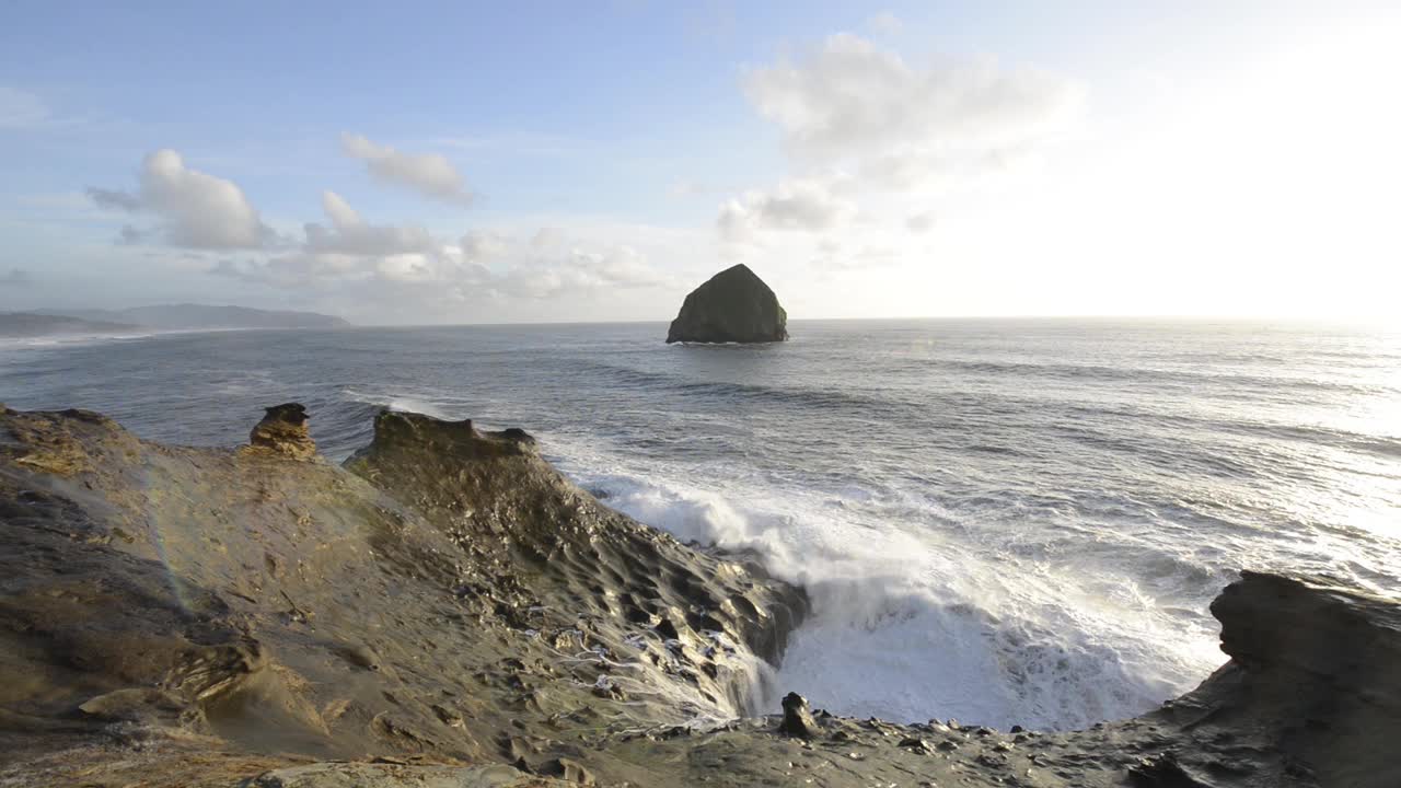 海滩上多云的天空下，海浪拍打着岩层视频素材