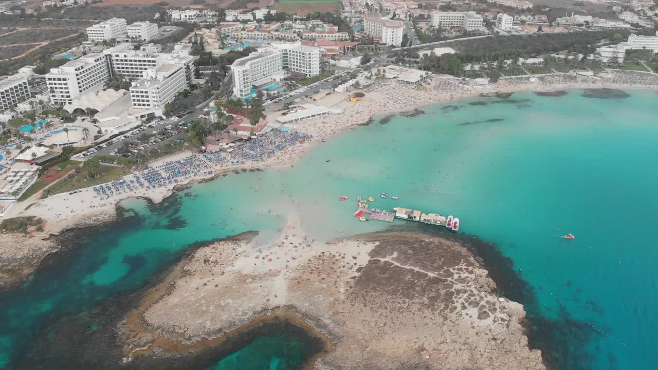 飞过小岛。景观。地中海和海岸。塞浦路斯。城市度假胜地。无人机视角。有岩石和石头的蓝色泻湖。山，海，天堂。俯视图，鸟瞰图。视频下载