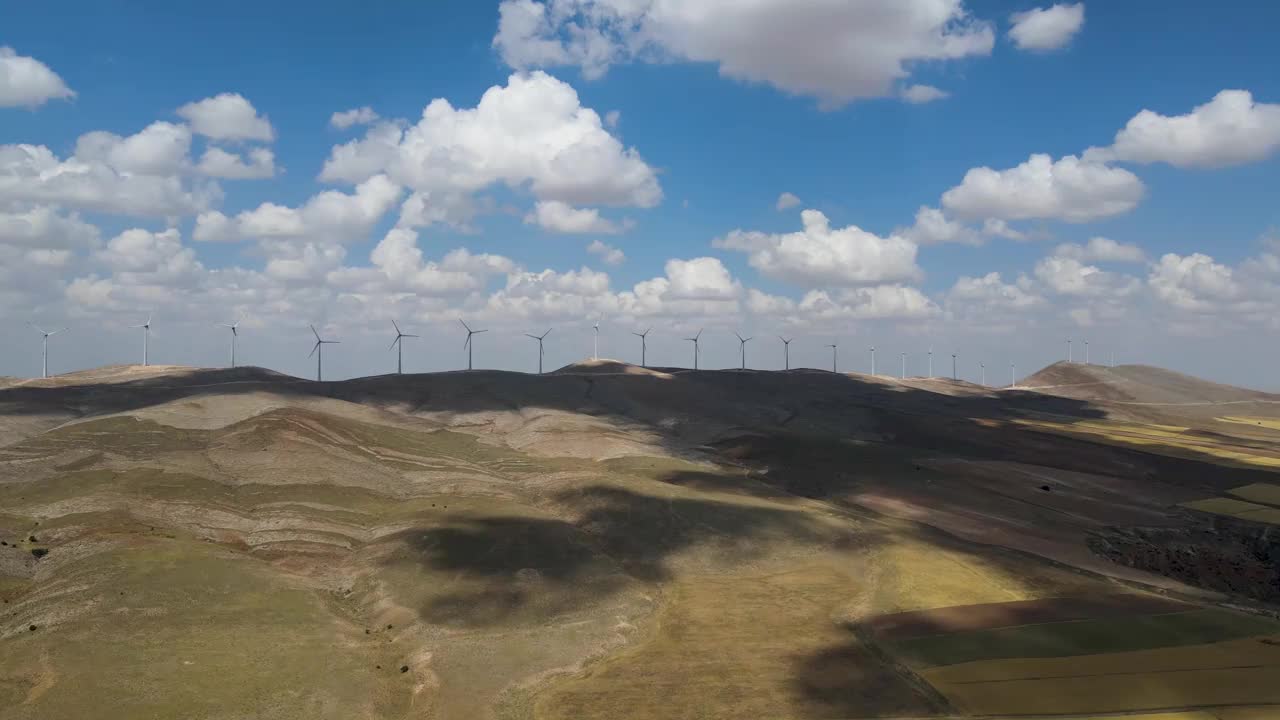 在土耳其明亮的天空下，用风力涡轮机俯瞰山上的草地和田野视频素材