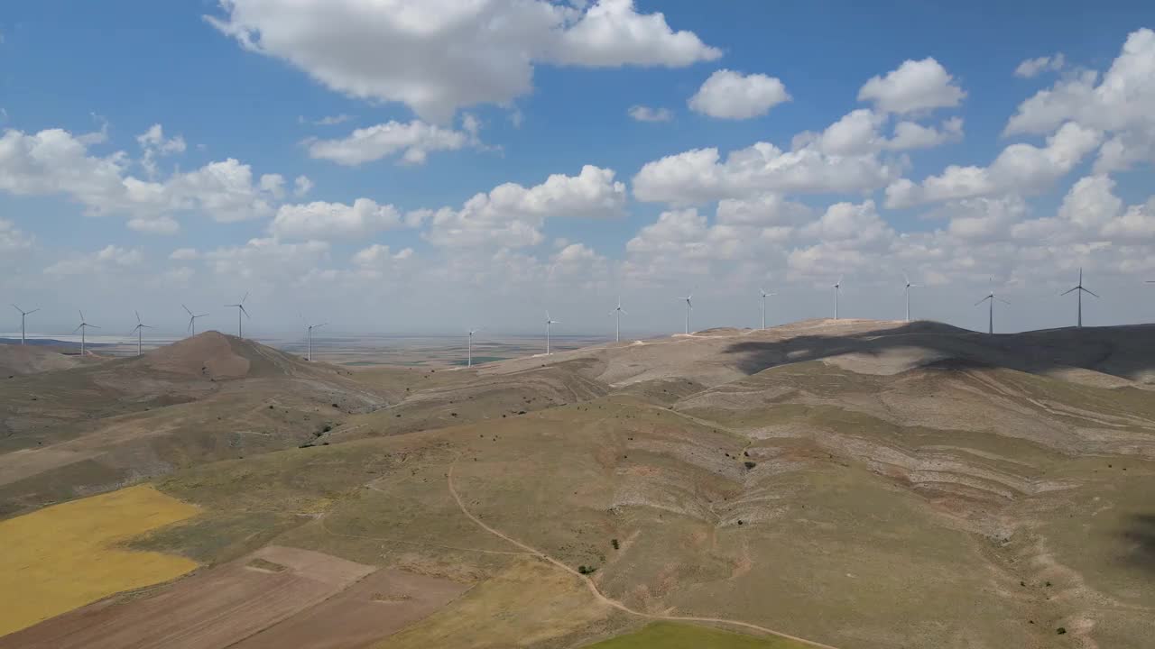 在土耳其明亮的天空下，用风力涡轮机俯瞰山上的草地和田野视频素材