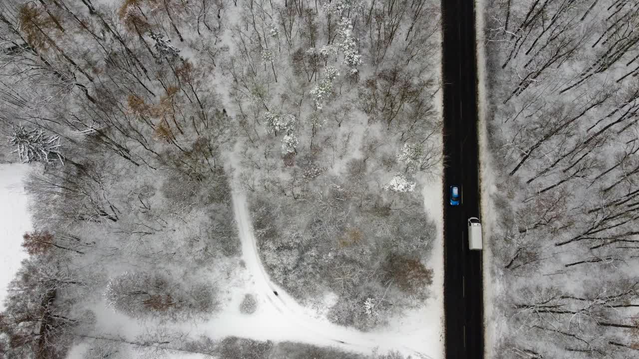 在公路上用汽车鸟瞰雪域，相机平行于道路飞行。在冬季森林上空低空飞行。视频素材