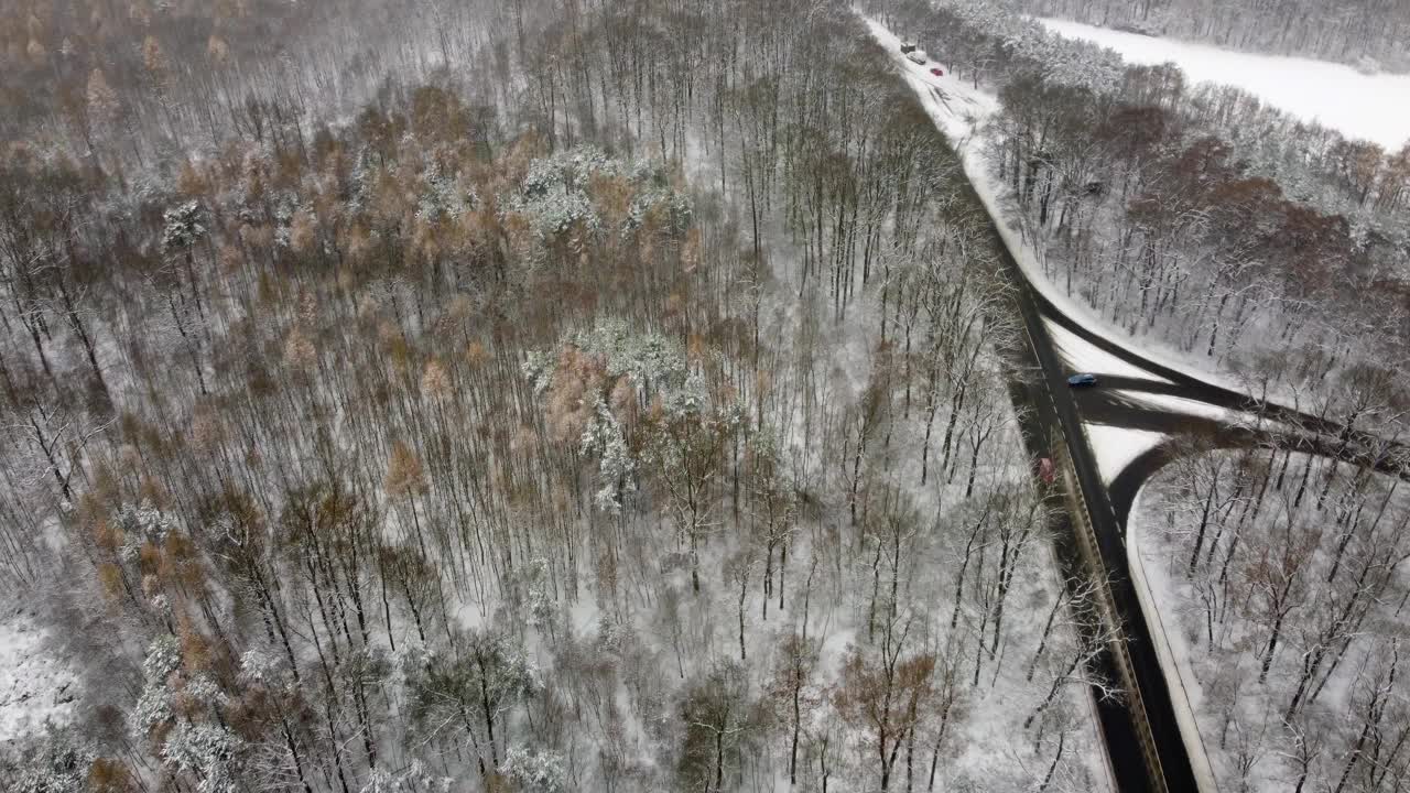 在公路上用汽车鸟瞰雪域，相机平行于道路飞行。在冬季森林上空低空飞行。视频素材