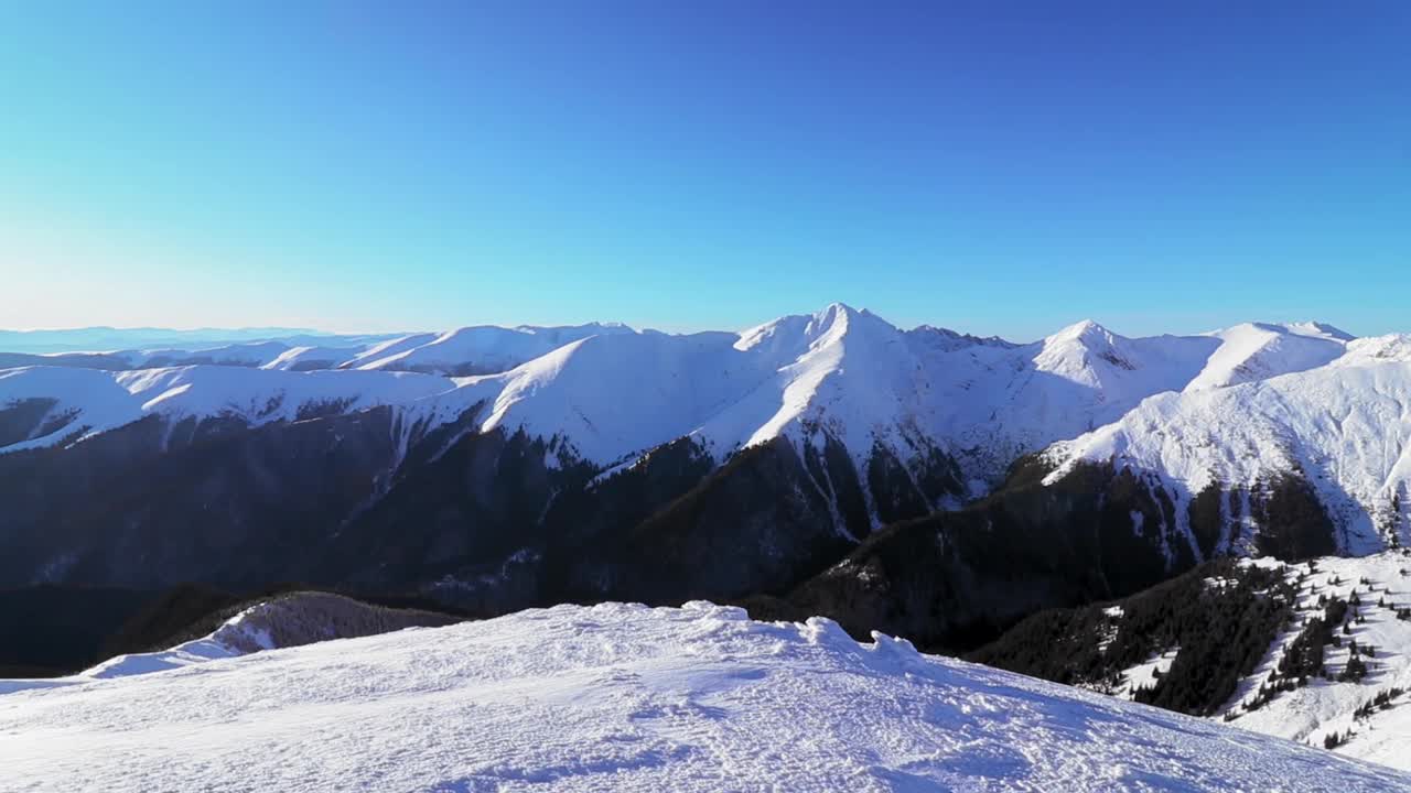 在冬天阳光明媚的日子里，白雪覆盖的小山的美丽景色视频素材